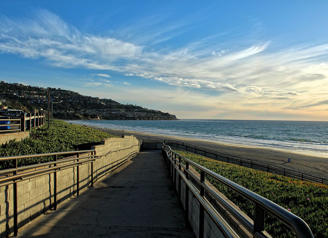 About Our Agency - Scenic View of a Walkway to the Beach Surrounded by Green Foliage in Torrence California at Sunset
