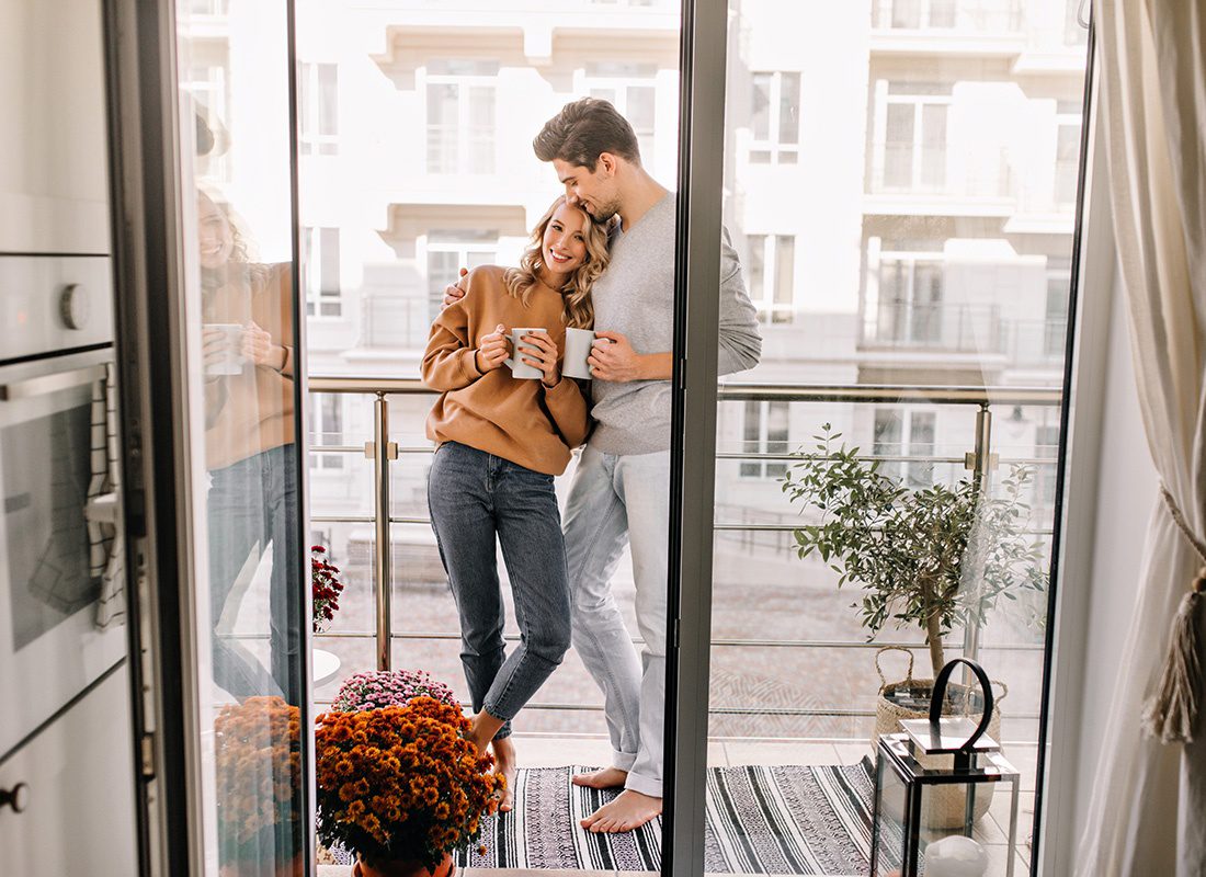 Read Our Reviews - Portrait of a Happy Newly Married Couple Standing on Their Balcony in Their New Apartment Drinking Coffee